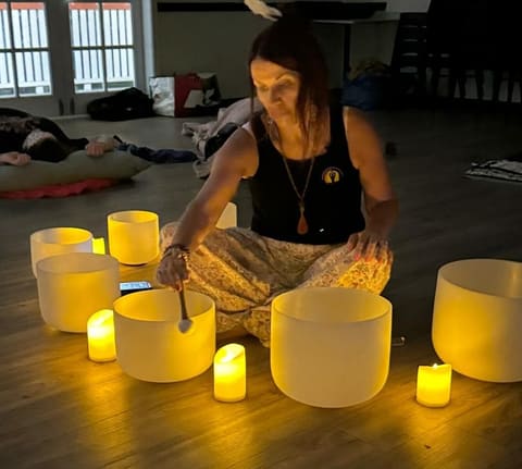 Dawn sitting among crystal singing bowls by candlelight