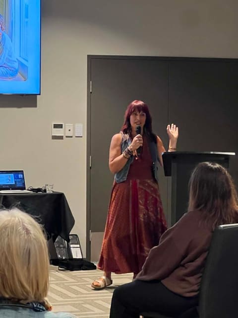 Dawn presenting with a microphone, mid-gesture