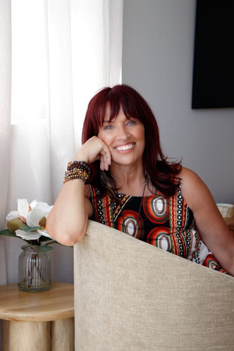 Dawn smiling, resting her chin on her hand beside a sunlit window